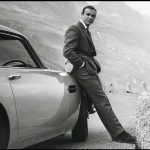 James Bond debout sur son Aston Martin